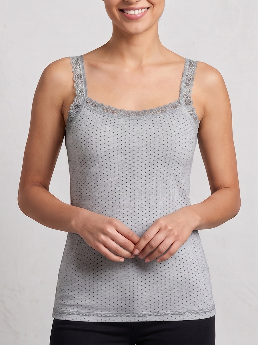 A woman wearing a light gray camisole tank top with a subtle polka dot pattern and lace trim along the scoop neckline, shown against a neutral light gray background.